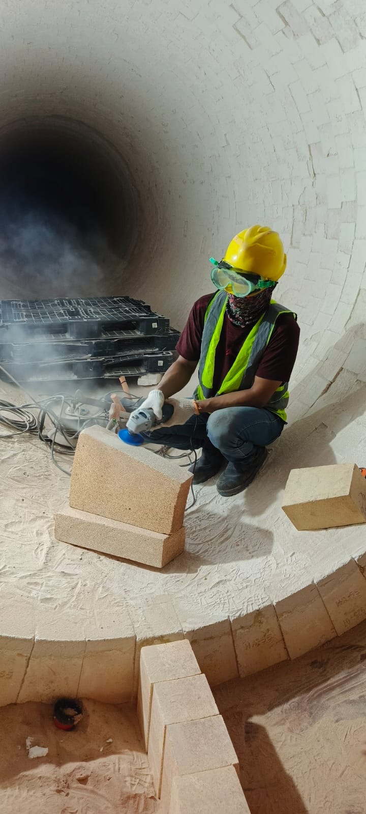 Pekerja memasang fire brick pada lining tungku dengan APD K3