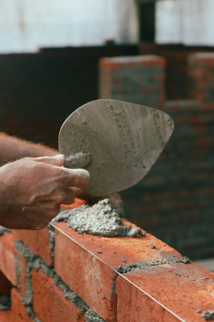 Tukang mengoles mortar dengan sendok semen